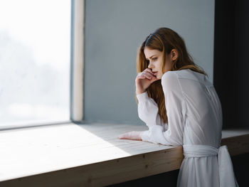 Young woman looking down while sitting on table