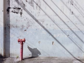 Fire hydrant on footpath against wall during sunny day