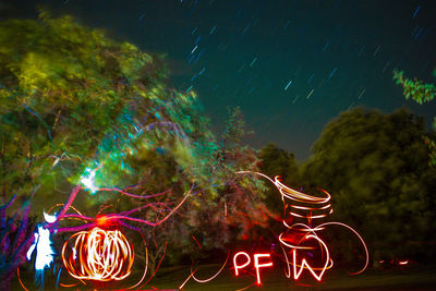 Illuminated ferris wheel against sky at night