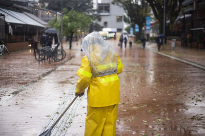 Rear view of boy on wet street during rainy season