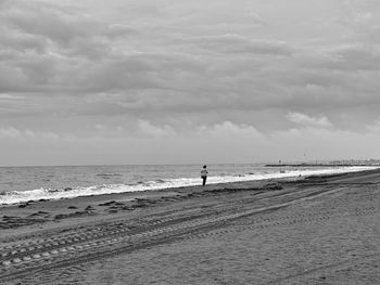 View of calm beach against cloudy sky