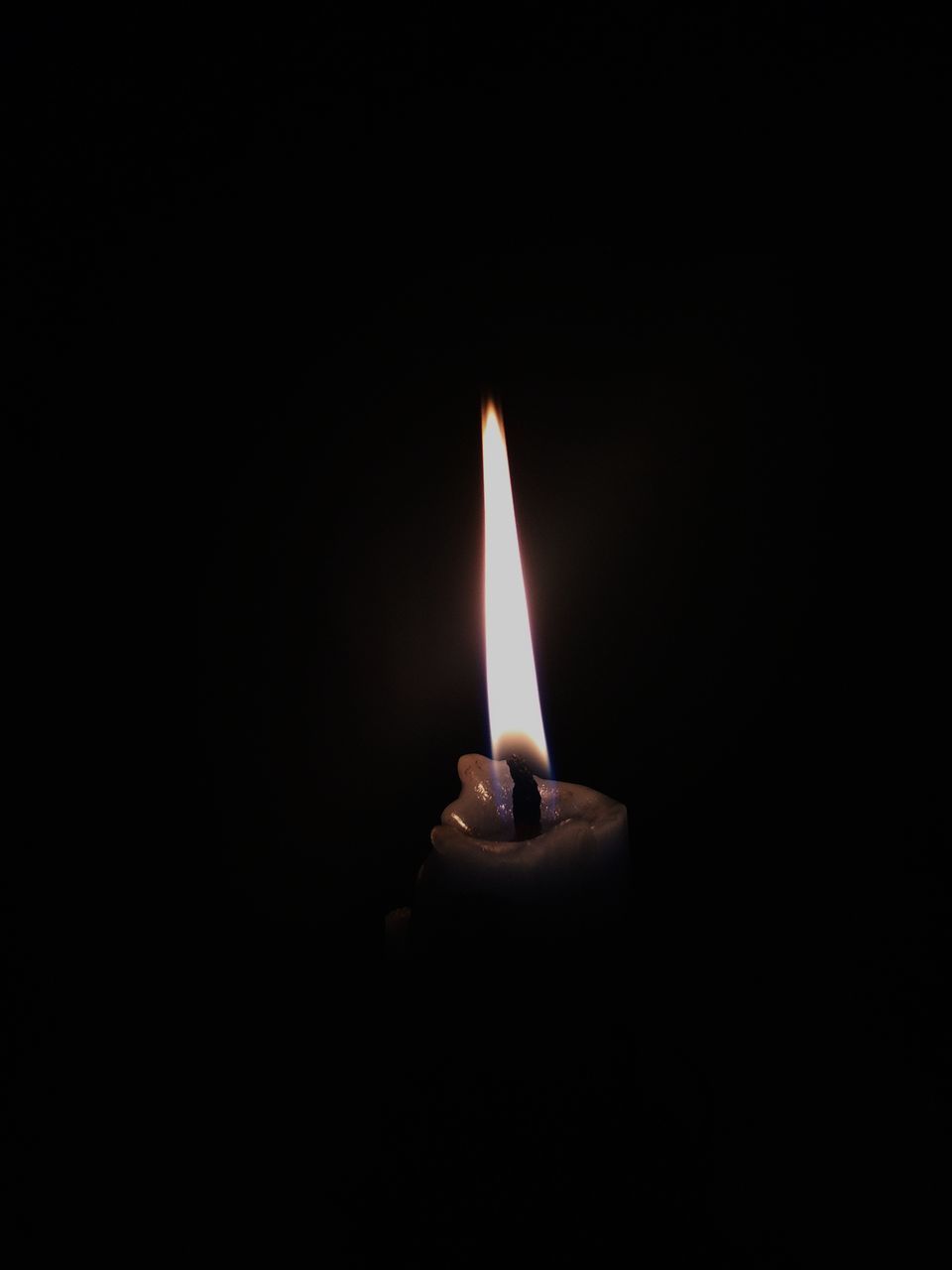 CLOSE-UP OF LIT CANDLE IN DARK