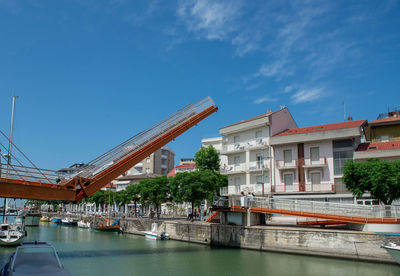 Buildings by river against sky