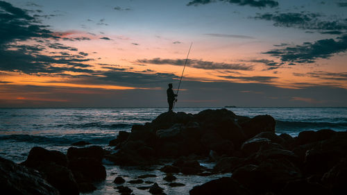 Scenic view of man fishing at sunset