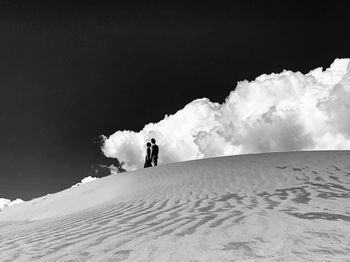Couple standing on dessert against sky