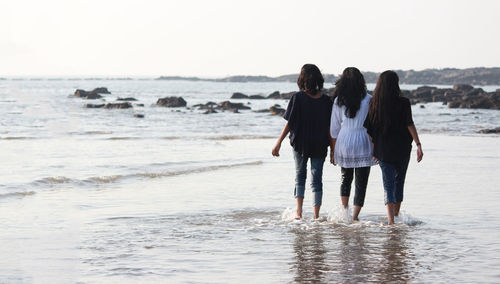 Rear view of women walking on beach