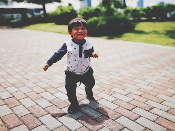 Cute baby boy walking on walkway at park during sunny day