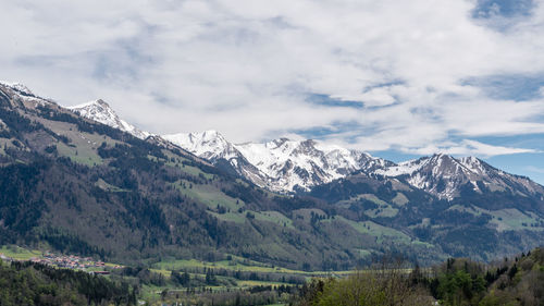 Scenic view of snowcapped mountains against cloudy sky