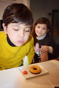 Boy blowing candle on table