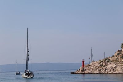 Sailboat sailing on sea against clear sky