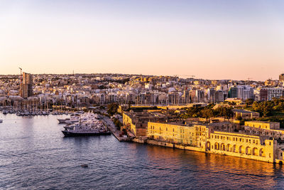 Scenic view of river by buildings against clear sky