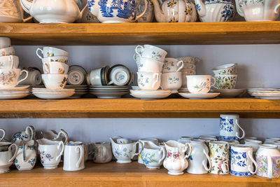 Assortment of hand painted ceramic floral pattern tea sets on shelves