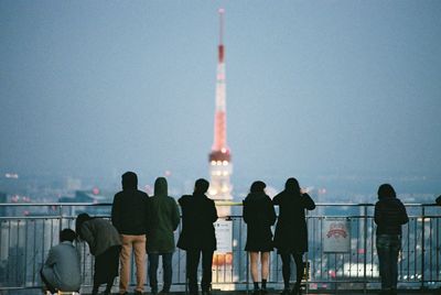 Rear view of people looking at illuminated tokyo tower against sky