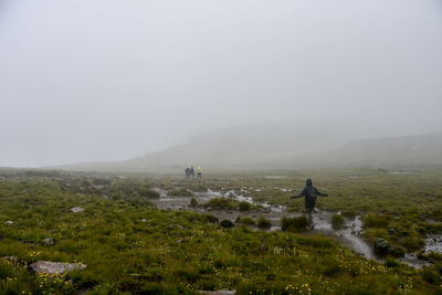 Hikers walking on landscape during foggy weather