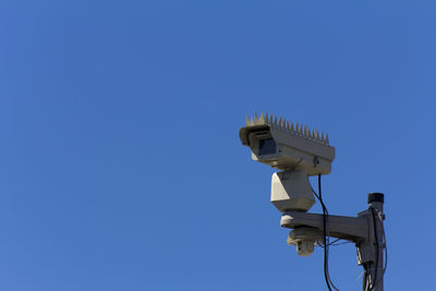 Low angle view of telephone pole against clear blue sky