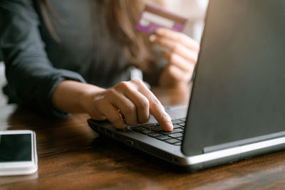 Midsection of woman using smart phone on table