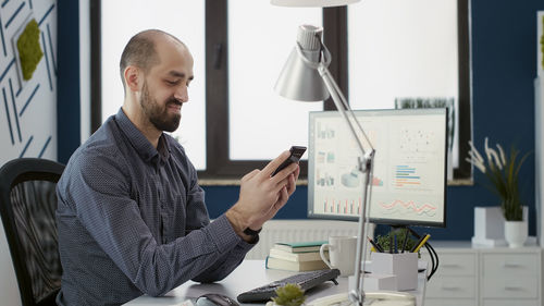 Side view of businessman using mobile phone in office