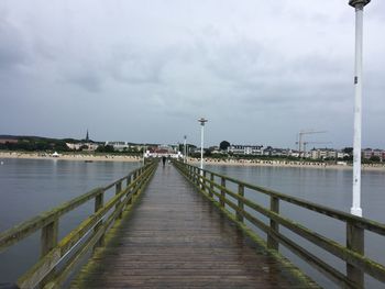 Empty pier over river against sky