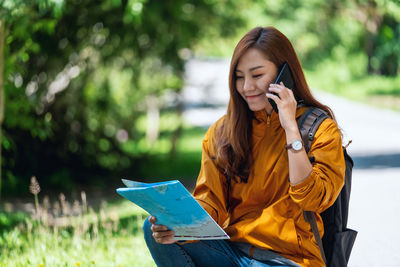 Young woman using laptop while sitting on field