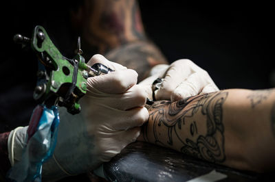 Cropped man tattooing on hand