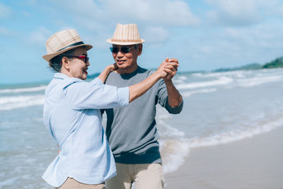 Happy couple dancing while standing at beach