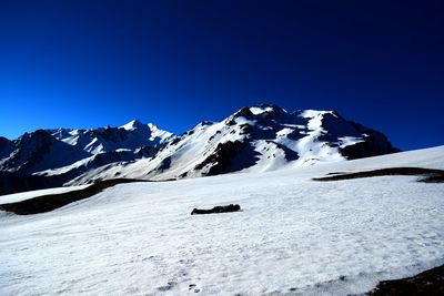 Scenic view of snowcapped mountains against clear blue sky