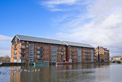 Buildings by river against sky