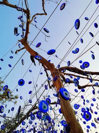 Low angle view of decoration hanging on tree against blue sky