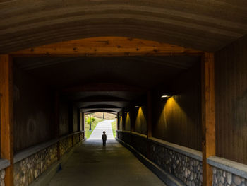 Rear view of man walking in tunnel