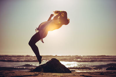 Full length side view of woman jumping on beach