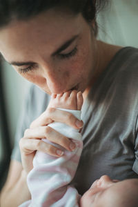 Side view of young woman kissing babys hand