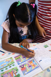 High angle view of girl making face on table