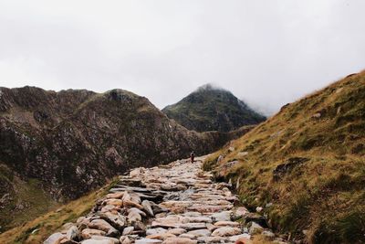 Footpath amidst rock formations against sky at snowdonia