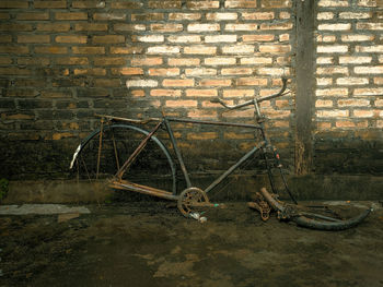 Abandoned bicycle against brick wall