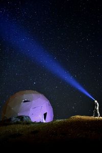 Man with illuminated headlamp standing against star field