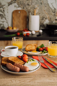 Home cooked english breakfast with cup of black coffee and orange juice in the kitchen	
