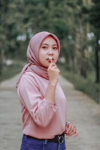 Portrait of woman wearing hijab eating lollipop