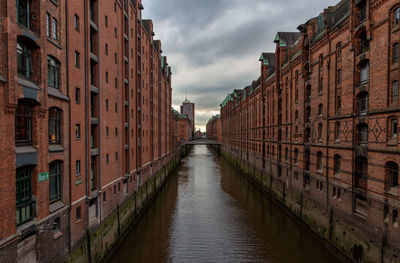 Canal amidst buildings in city against sky