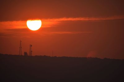 Silhouette of electricity pylon against sky during sunset