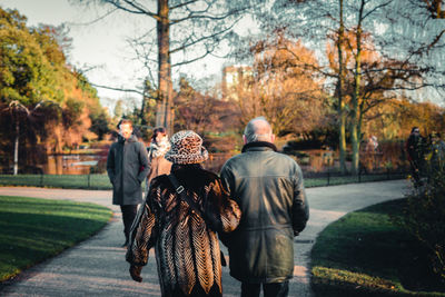 Rear view of people walking on road in park