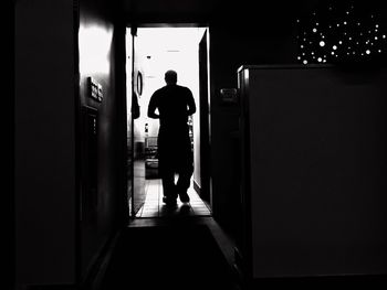 Rear view of man walking in domestic room at home