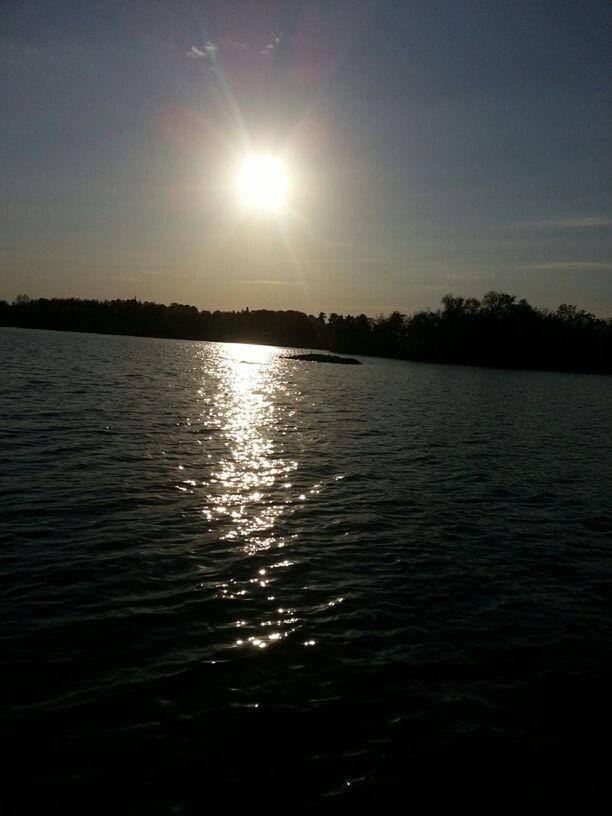 water, sun, tranquil scene, reflection, tranquility, scenics, sunset, beauty in nature, sunlight, waterfront, rippled, sky, nature, lake, sunbeam, silhouette, idyllic, lens flare, sea, outdoors