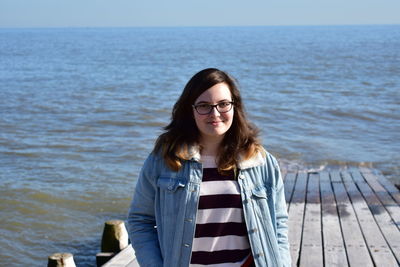 Portrait of smiling young woman standing against sea