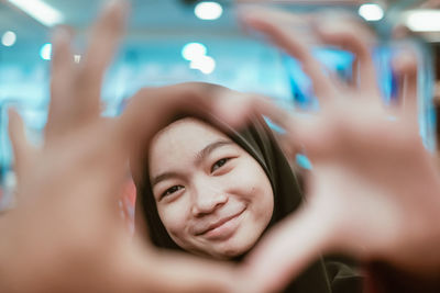Portrait of smiling teenager making heart shape with hands