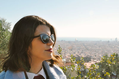 Woman wearing sunglasses in city against clear sky