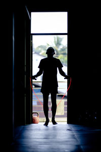 Rear view of silhouette woman standing at entrance of building