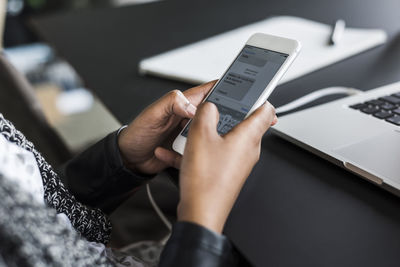 Hands of woman text messaging at desk, close-up