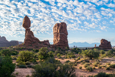 Rock formations on landscape against cloudy sky