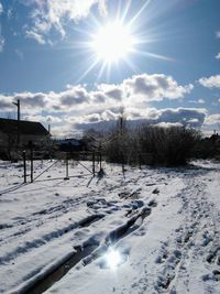 Scenic view of snow covered field against bright sun