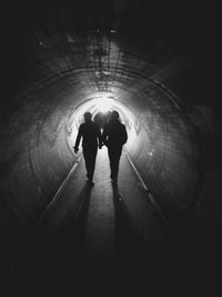 Silhouette of men walking in tunnel